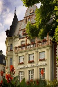 un grand bâtiment blanc avec un toit dans l'établissement Hotel Römischer Kaiser, à Trèves