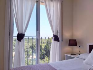 a bedroom with a large window with white curtains at Apartamento exterior en La Ametlla de Mar in L'Ametlla de Mar