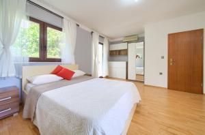 a bedroom with a white bed with a red pillow at Apartments Stolfa in Krk