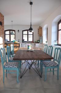a kitchen with a wooden table and blue chairs at Zakątek Sary in Jonkowo