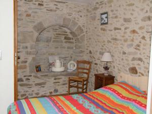 a bedroom with a stone wall with a bed and a chair at L'Tas De Cailloux in Cancale