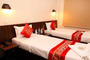 two beds in a hotel room with red pillows at Dream Nepal Hotel and Apartment in Kathmandu