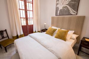 una camera da letto con un grande letto bianco con cuscini gialli di Indiana House Historical Center 5 pax a Siviglia