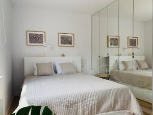 a white bedroom with a large bed and a mirror at Hilltom by the Sea in Rowy
