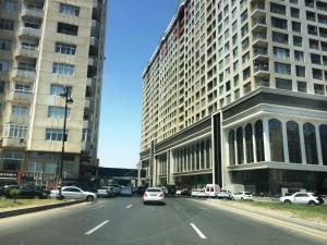 une voiture descendant dans une rue de la ville avec de grands bâtiments dans l'établissement Luxe Azure Apartment, à Baku