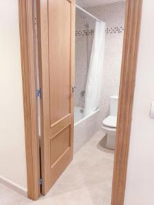 a bathroom with a toilet and a wooden door at Apartamento exterior en La Ametlla de Mar in L'Ametlla de Mar