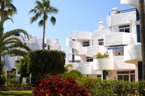 a white building with palm trees in front of it at Ona Campanario in La Cala de Mijas