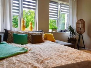 a bedroom with a large bed with pillows and windows at Apartments 4 You Hlonda in Tychy