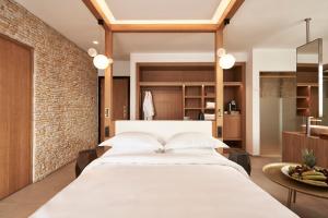 a bedroom with a large white bed and a brick wall at Myconian Naia - Preferred Hotels & Resorts in M&yacute;konos City