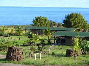 a building in a field next to the ocean at Heva Eco Lodge in Hanga Roa