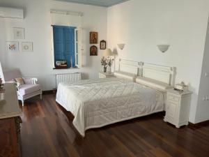 a bedroom with a large white bed and a chair at Palio Limani (Old Harbour) in Spetses