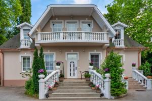 a pink house with a balcony and stairs at F57 - Frankó Családi Panzió in Balatonlelle