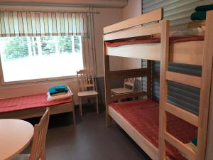 ein Schlafsaal mit Etagenbetten, einem Tisch und einem Fenster in der Unterkunft Luontoleirikeskus Lankari in Seinäjoki