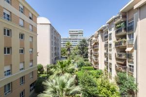 an apartment building with palm trees and buildings at Appartement Palais Milton in Cannes