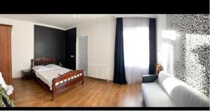 a bedroom with a bed and a couch and a window at guest house Telavi XXI in Tʼelavi
