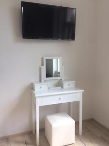 Biały stół z lustrem i telewizor na ścianie w obiekcie Apartmán nad Imperiálem w Karlowych Warach