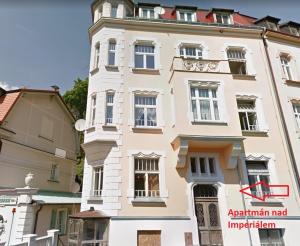wysoki biały budynek z czerwoną strzałą w obiekcie Apartmán nad Imperiálem w Karlowych Warach