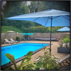 a blue swimming pool with an umbrella and chairs at Domaine du Blanc Pignon in La Calotterie