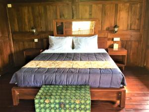 um quarto com uma cama e uma parede de madeira em Kubu Taru em Sidemen