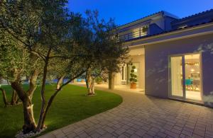 a house with a lawn and trees in front of it at Villa Vale in Kornić