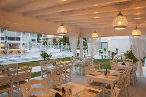 a restaurant with white tables and chairs and lights at Laguna Resort Boutique Hotel in Hanioti