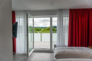 a bedroom with red curtains and a view of a balcony at Pension Haas-Hotel am Turm in Rottweil