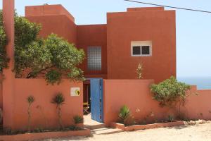 a red house with a blue door and a fence at Riad Daribis vue sur la mer Agadir in Rbat