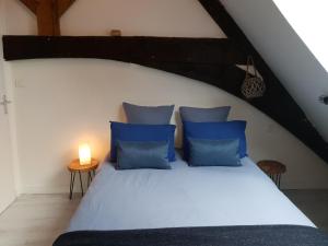 um quarto com uma cama com almofadas azuis e uma vela em Ty Clément em Dinan