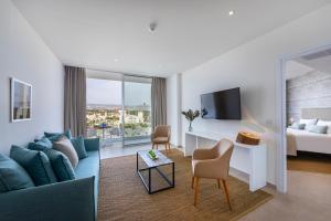 um quarto de hotel com um sofá e uma cama e uma televisão em Leonardo Plaza Cypria Maris Beach Hotel & Spa em Pafos