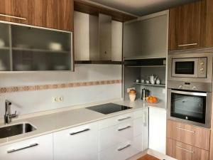 a kitchen with white cabinets and a sink and a microwave at Casa Pío Nigrán, vistas Islas Cíes in Nigrán