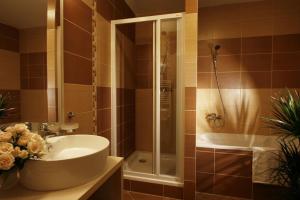 La salle de bains est pourvue d'une baignoire, d'un lavabo et d'une douche. dans l'établissement Hotel Crocus, à Štrbské Pleso
