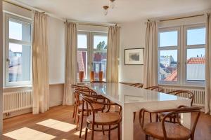 a dining room with a table and chairs and windows at Joachim 8 Maisonette Apartment in Berlin