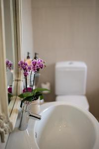 a bathroom sink with a vase with purple flowers in it at Luxury Beach Apartments in Amanzimtoti