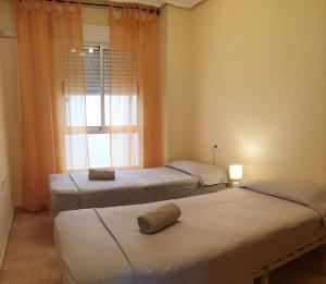 three beds in a room with a window at Apartamento Cervantes in Guardamar del Segura