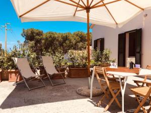 patio con tavolo, sedie e ombrellone di Villino I Sugheri a Marciana Marina