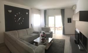 a living room with a couch and a clock on the wall at Apartment Nima Orebic in Orebić