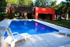 a swimming pool with two chairs and a house at La Wet in Tartagal