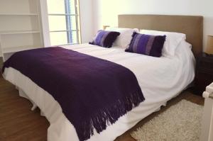 a large bed with purple and white sheets and pillows at Apart Hotel Quillango in Punta Arenas
