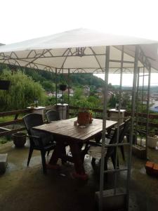 une table et des chaises en bois sous un parasol dans l'établissement Apartment AMRA, à Tuzla