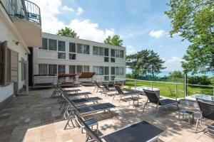 a patio with chairs and tables and a building at Magaspart Panzió in Balatonföldvár