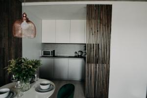 eine Küche mit weißen Schränken, einem Tisch und einer Mikrowelle in der Unterkunft ERTA Anykščių Namai in Anykščiai