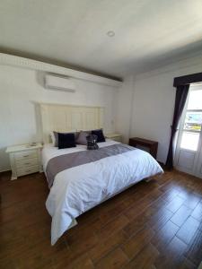 1 dormitorio con 1 cama grande y suelo de madera en Hotel Estancia Real, en Tepatitlán de Morelos