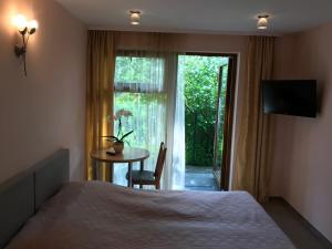 a bedroom with a bed and a table and a window at Vila Saulė in Palanga
