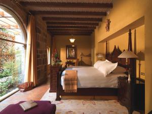 a bedroom with a large bed and a large window at Monasterio, A Belmond Hotel, Cusco in Cusco