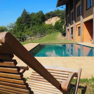 a wooden bench sitting next to a swimming pool at Mas Cal Sastre in Sant Hilari Sacalm