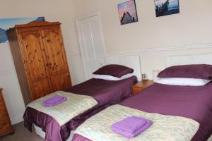 two beds in a room with purple sheets at Napier Town House - Self Catering - Guesthouse Style - Twin and Double Rooms in Workington