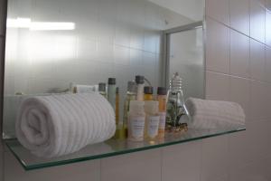 Coluni Sport & Resort srl في غرافينا إن بوليا: رف في الحمام مع ورق التواليت والمناشف +33 صورة