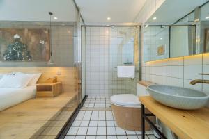a bathroom with a sink and a toilet and a bed at Moganshan Pinhouwu Hotel in Deqing