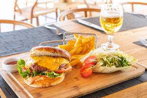 a wooden tray with a sandwich and chips and a glass of beer at Hotel Vita Bella Resort & Spa in Gundogan