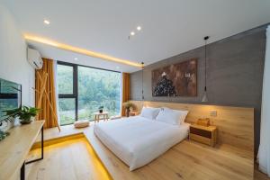 a bedroom with a large white bed and a large window at Moganshan Pinhouwu Hotel in Deqing